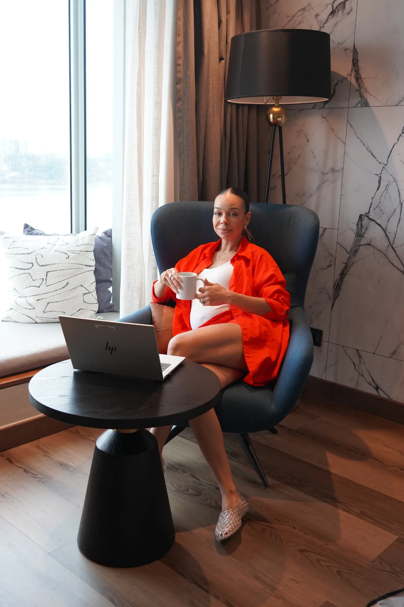 Courtney seated with her laptop and a cup of coffee